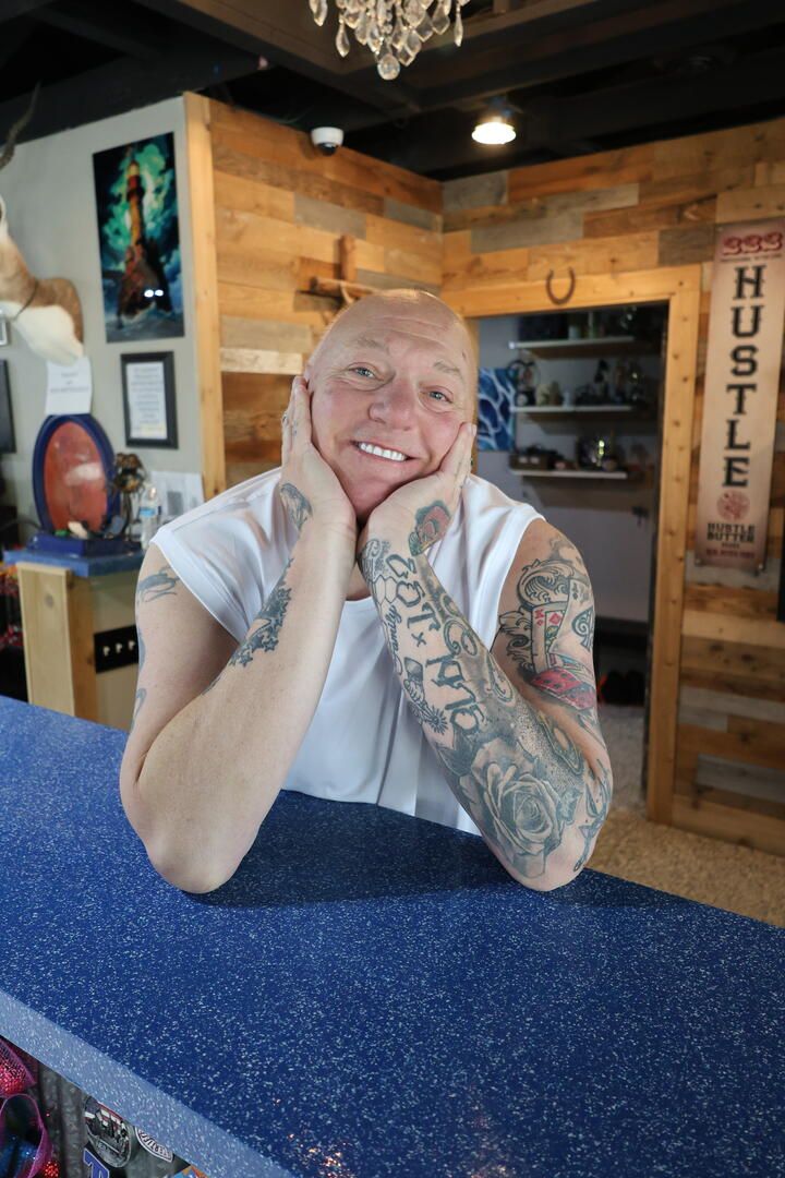 Joshua Karnes smiling at the front desk of Dragonfly Tattoo KC.